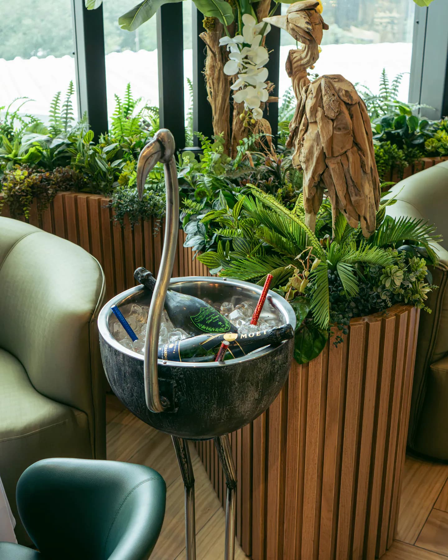 Botella de Moët & Chandon en hielo dentro de una champanera con forma de flamenco, junto a la vegetación del salón