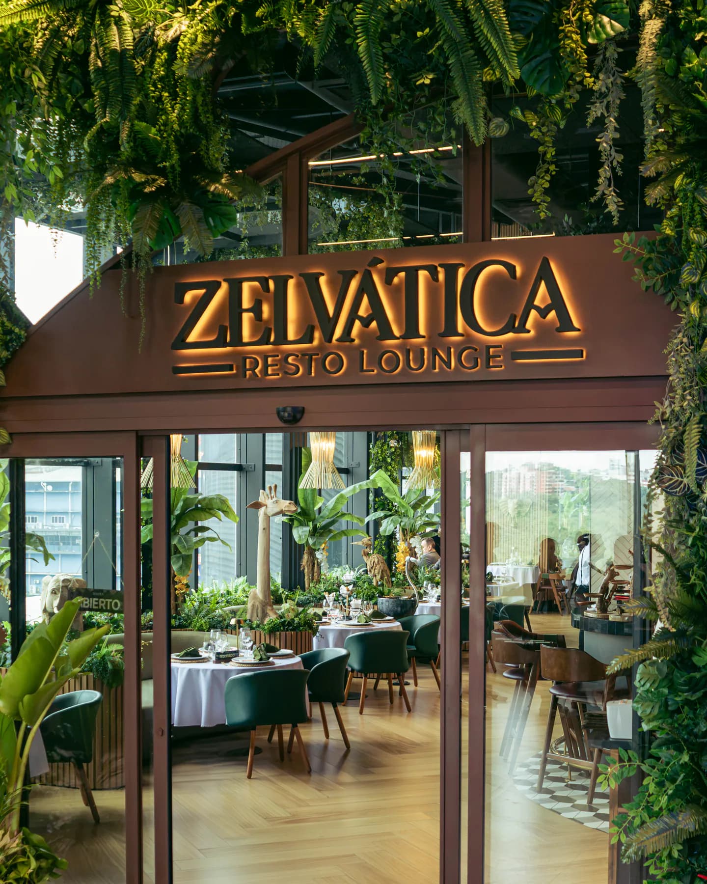 Acceso a Zelvática con el cartel Resto Lounge retroiluminado y el salón al fondo