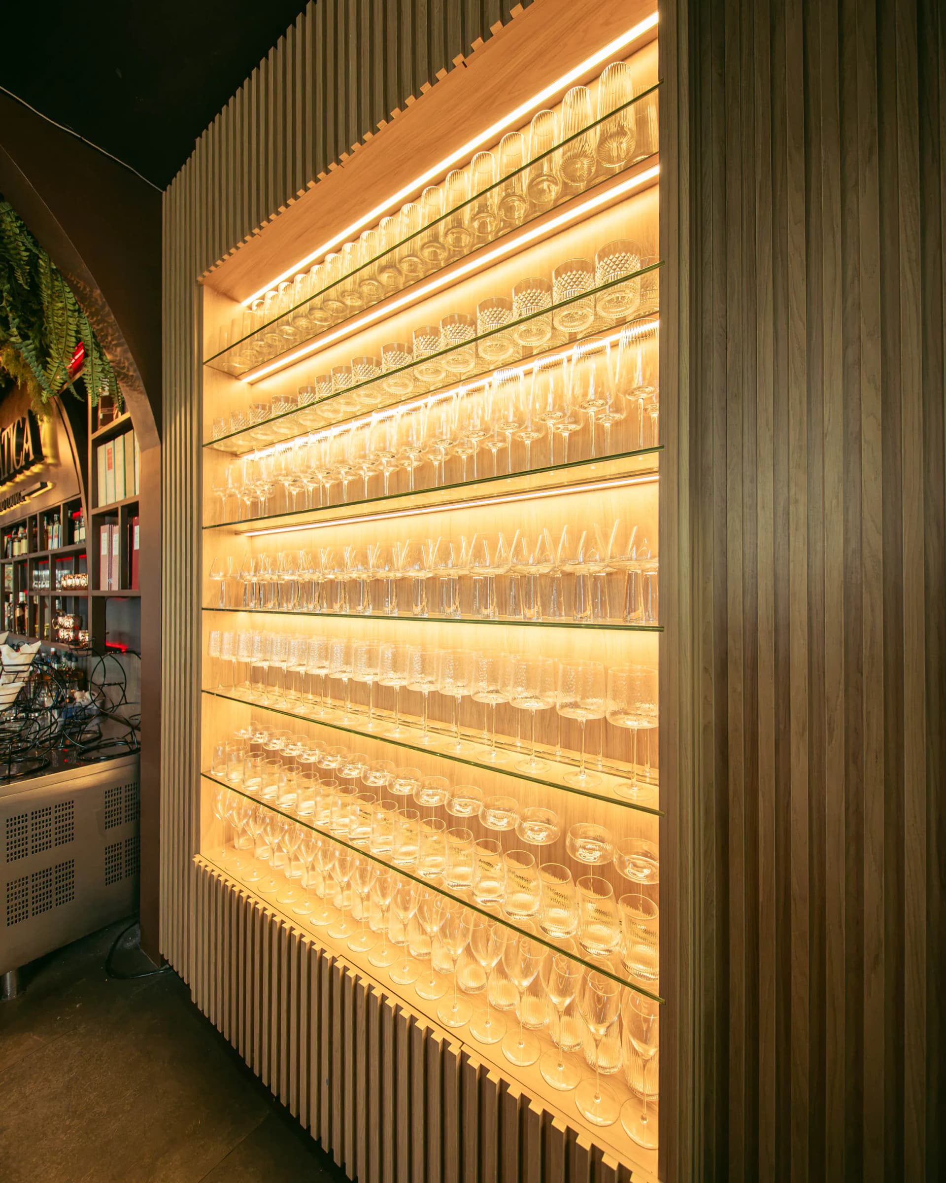 Estantería de madera con copas retroiluminadas en luz cálida