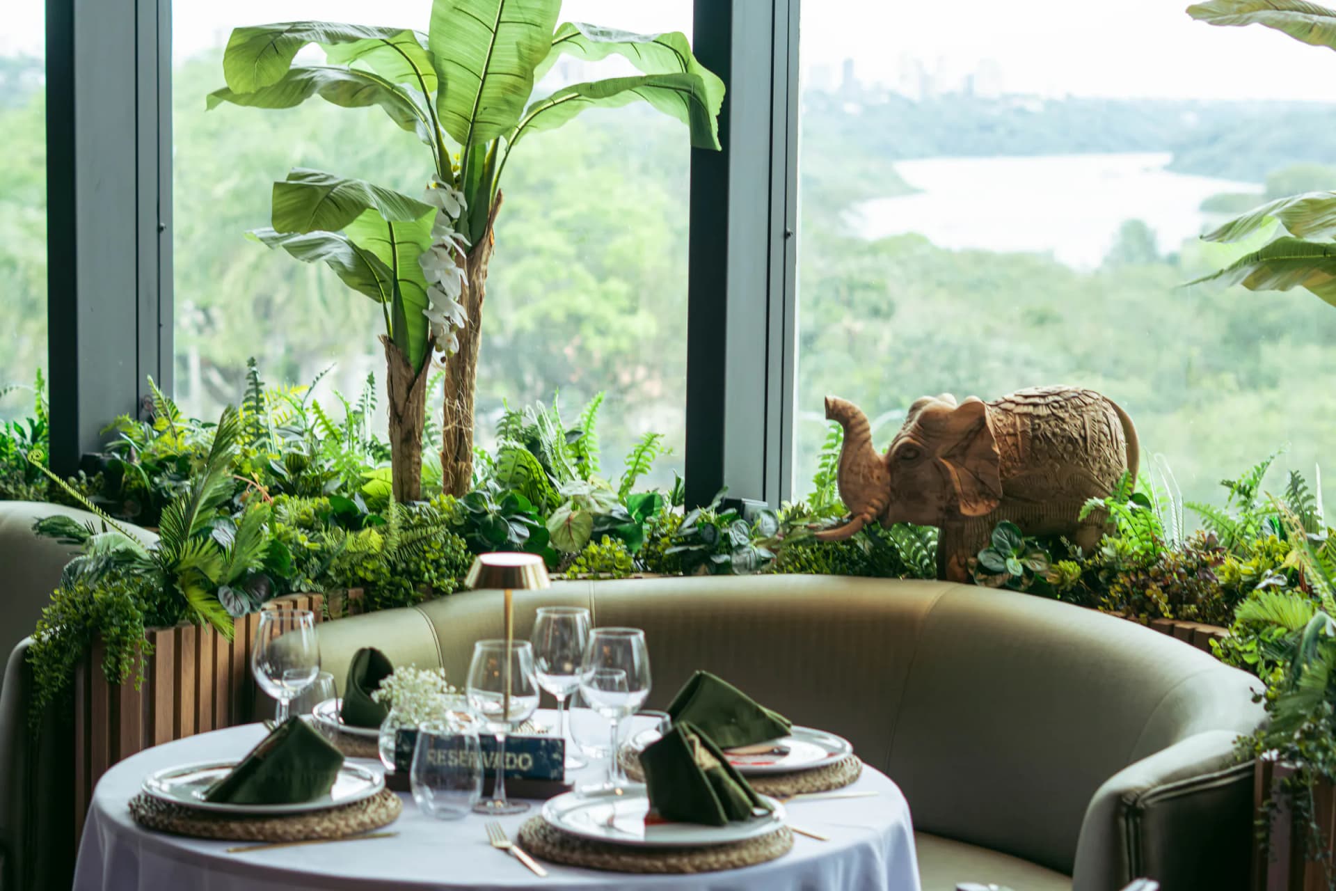 Mesa junto al ventanal con la vista del río y la ciudad, un elefante de madera y un sofá curvo